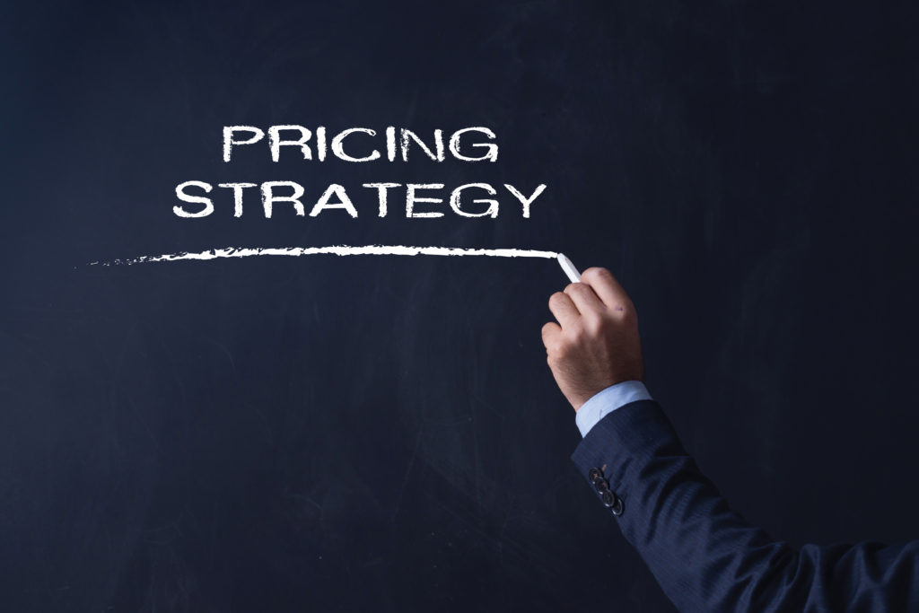 Businessman writing PRICING STRATEGY on Blackboard